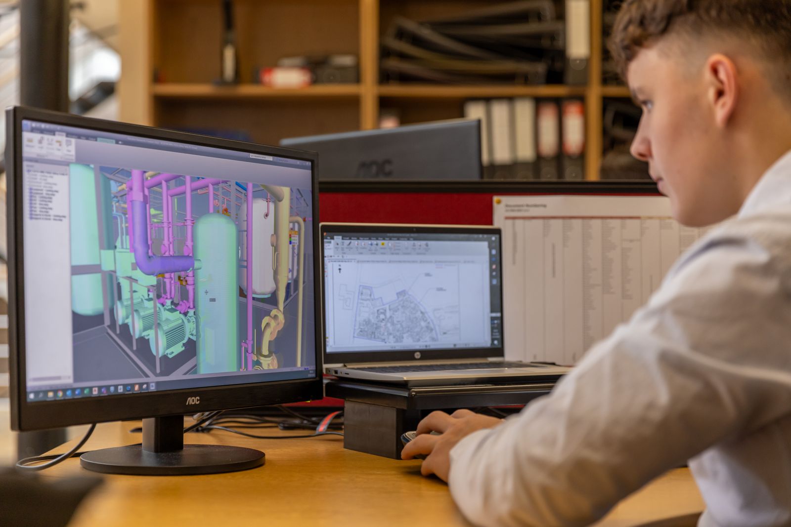 Engineer reviewing a 3D CAD model on dual monitors — representative photography